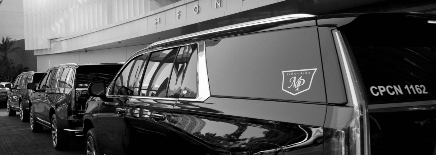 Black-and-white photo of a fleet of black Cadillac Escalade SUVs with MP Limousine branding lined up under the porte-cochère of the Fontainebleau, the lead vehicle marked CPCN 1162.