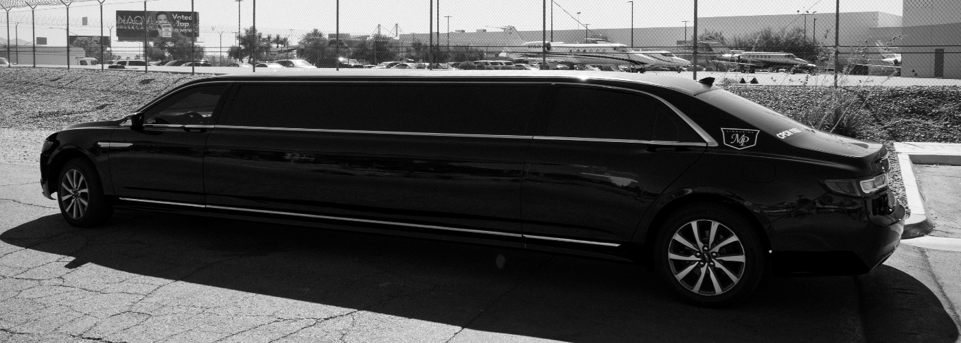 Black-and-white side profile of a black stretch limousine with MP Limousine branding on the rear door, parked outdoors near an airfield with private jets visible in the background.